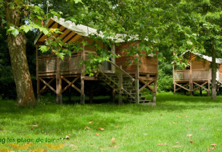 Eco lodge cabins among trees at Camping Seasonova Les Plages de Loire in France, lush green summer scene.