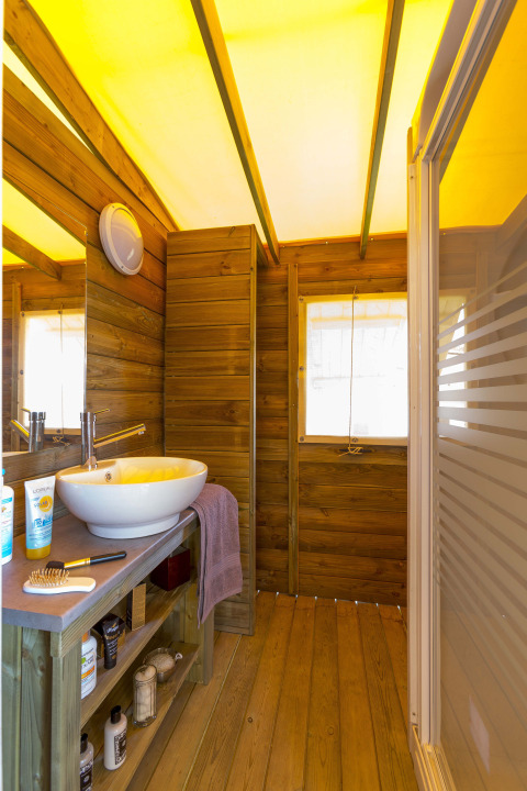 Eco lodge cabin bathroom at Camping Seasonova Les Plages de Loire, France, with wood interior and vessel sink.