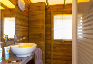 Badkamer van de Eco lodge bij Camping Seasonova Les Plages de Loire, Frankrijk, met hout en waskom.
