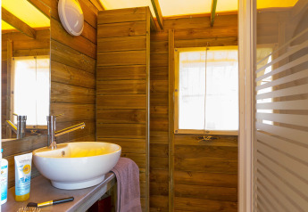 Modernes Holzbad mit Waschbecken und Spiegel in der Eco lodge bei Camping Seasonova Les Plages de Loire, Frankreich.
