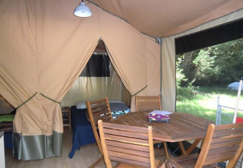 Binnenzicht van een Bungalodge bij Camping Seasonova Les Plages de Loire in Frankrijk met houten tafel en stoelen.