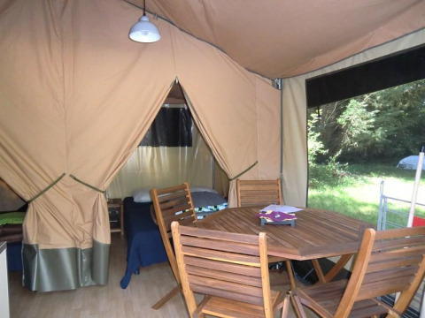 Binnenzicht van een Bungalodge bij Camping Seasonova Les Plages de Loire in Frankrijk met houten tafel en stoelen.