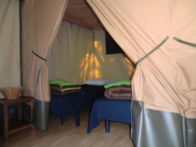 Interior acogedor de una Bungalodge con dos camas y muebles de madera en Camping Seasonova Les Plages de Loire, Francia.