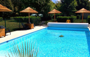 Piscina climatizada con sombrillas de paja en Camping Seasonova Le Martinet, Centre-Val de Loire, Francia.