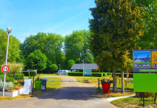 Toegang tot Camping Seasonova Le Martinet in Centre-Val de Loire, Frankrijk, met bomen en kleurrijke borden.