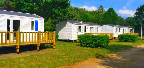 Weiße Mobilheime im Ferienpark Camping Seasonova Le Martinet, umgeben von Natur in Centre-Val de Loire, Frankreich.