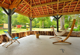 Covered outdoor seating area with hammock and chair at Camping Seasonova Etang de la Vallée, France.
