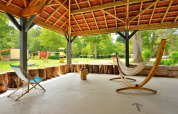 Covered outdoor seating area with hammock and chair at Camping Seasonova Etang de la Vallée, France.