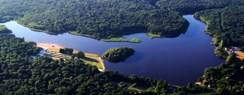 Luftaufnahme vom Camping Seasonova Etang de la Vallée mit See und dichtem Wald im Centre-Val de Loire, Frankreich.