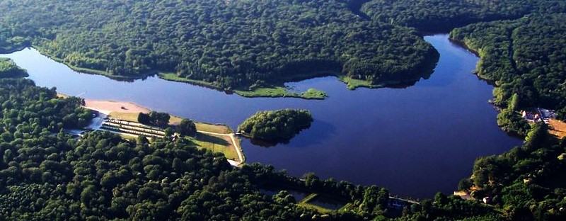 Aerial view of Camping Seasonova Etang de la Vallée showing a large lake and lush forest in Centre-Val de Loire, France.