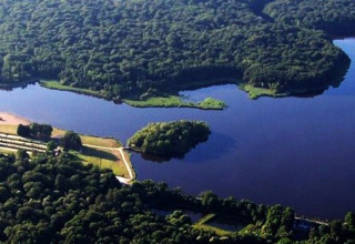 Vista aerea di Camping Seasonova Etang de la Vallée con un grande lago circondato da boschi nel Centre-Val de Loire, Francia.