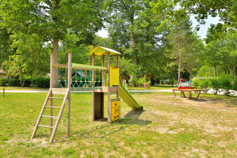 Playground with slide and climbing structure in a green park at Camping Seasonova Etang de la Vallée, France.