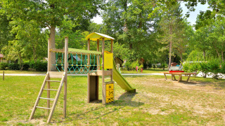 Spielplatz mit Rutsche und Klettergerüst im Grünen im Camping Seasonova Etang de la Vallée, Frankreich.