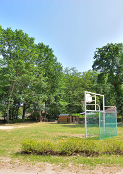 Zwei Basketballplätze im Freien bei Camping Seasonova Etang de la Vallée, umgeben von grünen Bäumen.