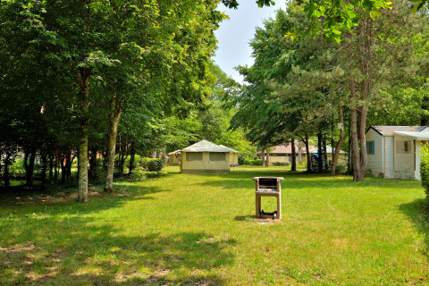 Campeggio con prato verde, tende, case mobili e barbecue all’Etang de la Vallée, Centre-Val de Loire.
