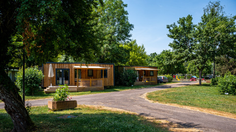 Houten huisjes op Camping Seasonova Vesoul in Bourgogne-Franche-Comté, Frankrijk, tussen het groen.