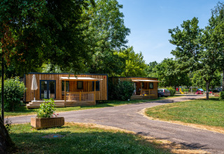 Houten huisjes op Camping Seasonova Vesoul in Bourgogne-Franche-Comté, Frankrijk, tussen het groen.