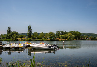 Boats and pedalos docked by the calm water at Camping Seasonova Vesoul, Bourgogne-Franche-Comté, France.