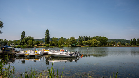 Bateaux et pédalos amarrés sur l’eau calme au Camping Seasonova Vesoul, Bourgogne-Franche-Comté, France.