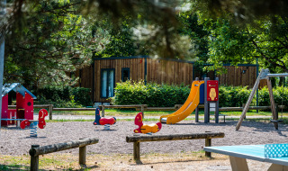 Parque infantil con tobogán y columpios en Camping Seasonova Vesoul, Bourgogne-Franche-Comté, Francia.