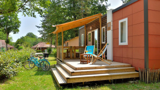 Outdoor view of Cottage New Valley with a sunny deck, lounge chairs, bicycles, and lush greenery around.