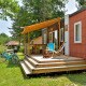 Udendørs scene ved Cottage New Valley, viser en hyggelig terrasse, cykler og grøn beplantning omkring hytten.