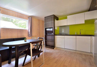 Moderne keuken en eethoek met houten panelen en groene accentmuur in Cottage New Valley.