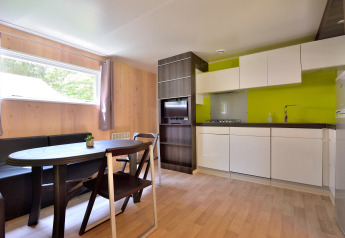 Modern kitchen and dining area with wood paneling and green accent wall in Cottage New Valley.