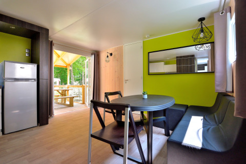 Moderne leefruimte in Cottage New Valley met eettafel, zetel, koelkast en toegang tot het terras.
