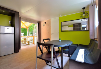 Moderne opholdsstue i Cottage New Valley med spisebord, sofa, køleskab og udgang til terrasse.