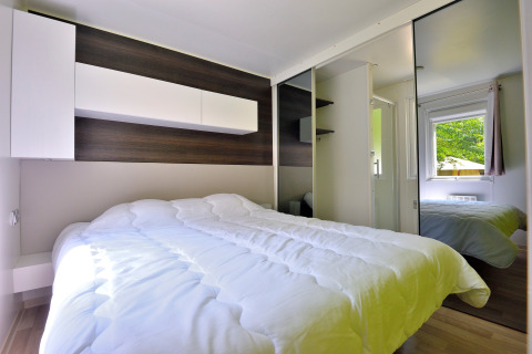 Moderne slaapkamer in Cottage New Valley met dubbel bed, spiegelkast en raam met zicht op de natuur.