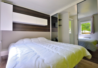 Dormitorio moderno en Cottage New Valley con cama doble, armario con espejo y ventana con vista natural.