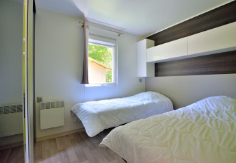 Bright bedroom in Cottage New Valley featuring two single beds, white bedding, and modern storage units.
