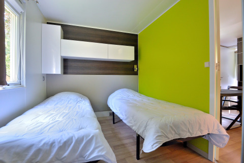 Habitación con dos camas individuales, paredes claras, detalles de madera y pared verde lima en Cottage New Valley.