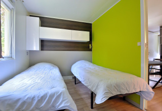 Habitación con dos camas individuales, paredes claras, detalles de madera y pared verde lima en Cottage New Valley.