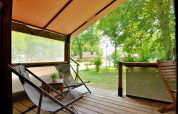 Vista desde la terraza de la tienda safari Lodge Victoria en Camping Seasonova Etang de la Vallée, con sillas y árboles.