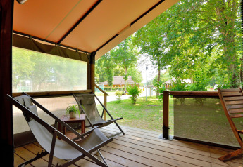 Zicht vanaf Lodge Victoria safaritent terras op Camping Seasonova Etang de la Vallée, met stoelen en groen.