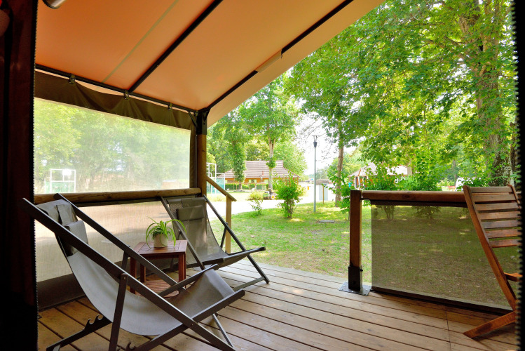 Vista desde la terraza de la tienda safari Lodge Victoria en Camping Seasonova Etang de la Vallée, con sillas y árboles.