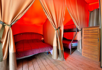 Interno di una tenda safari con letto matrimoniale e letto a castello al Lodge Victoria, Camping Seasonova Etang de la Vallée, Francia.