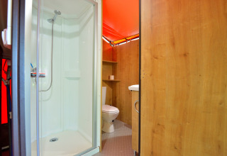 Bathroom inside Lodge Victoria safari tent at Camping Seasonova Etang de la Vallée featuring shower and toilet.