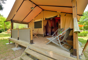 Tienda safari tipo lodge con terraza de madera y tumbonas en Camping Seasonova Etang de la Vallée, Francia.