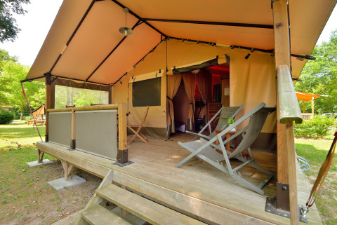 Safari lodge tent with wooden deck and reclining chairs at Camping Seasonova Etang de la Vallée in France.