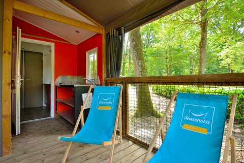 Cozy Mobilodge cabin at Camping Seasonova Etang de la Vallée in France with two blue deck chairs and forest views.