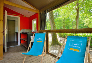 Gemütliche Mobilodge-Hütte bei Camping Seasonova Etang de la Vallée in Frankreich, mit zwei blauen Liegestühlen auf der Terrasse.