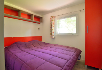 Camera da letto al Mobilodge del Camping Seasonova Etang de la Vallée in Francia con piumone viola.