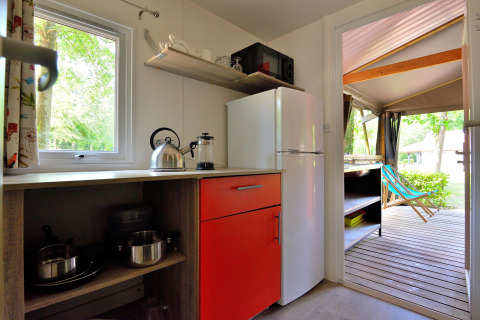 Cucina di Mobilodge con frigo, armadio rosso e terrazza al Camping Seasonova Etang de la Vallée, Francia.