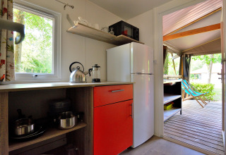 Mobilodge-keuken met koelkast, kast en zicht op terras bij Camping Seasonova Etang de la Vallée, Frankrijk.