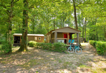 Zwei Mobilodge-Hütten auf dem Camping Seasonova Etang de la Vallée in Frankreich, umgeben von Wald.