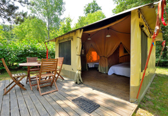 Safari-lodgetent met houten terras en buitenmeubilair bij Camping Seasonova Etang de la Vallée in Frankrijk.