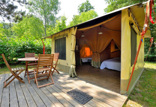 Safari-Lodgezelt mit hölzerner Terrasse und Gartenmöbeln bei Camping Seasonova Etang de la Vallée in Frankreich.
